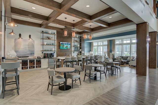 dining space with beamed ceiling, light parquet flooring, coffered ceiling, and ornate columns