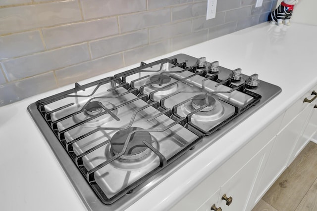 interior details with gas stovetop, white cabinetry, and wood-type flooring