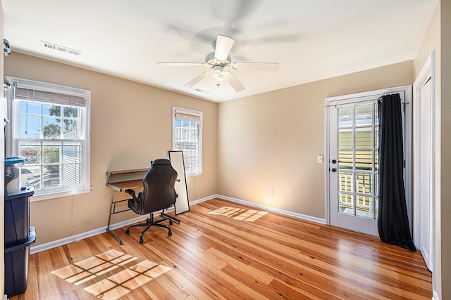 office area with visible vents, plenty of natural light, light wood-style flooring, and a ceiling fan