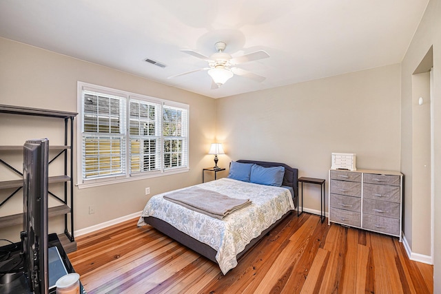 bedroom featuring visible vents, baseboards, and wood finished floors