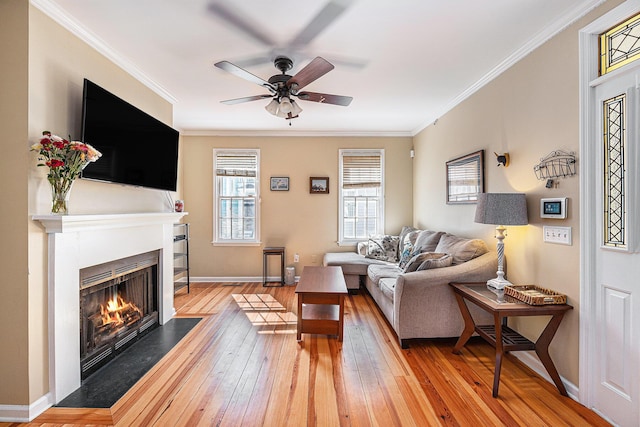 living room with crown molding, light wood-style flooring, a fireplace with flush hearth, and baseboards