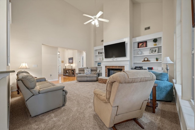 carpeted living area featuring a high ceiling, ceiling fan, a fireplace, built in features, and baseboards