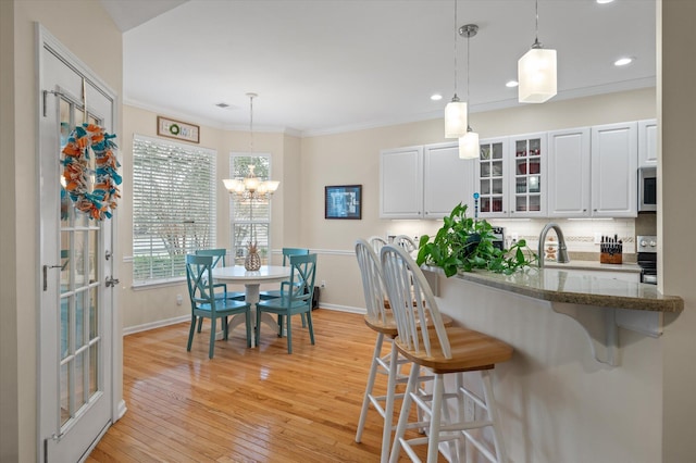 kitchen with a kitchen breakfast bar, glass insert cabinets, tasteful backsplash, recessed lighting, and light wood-style floors
