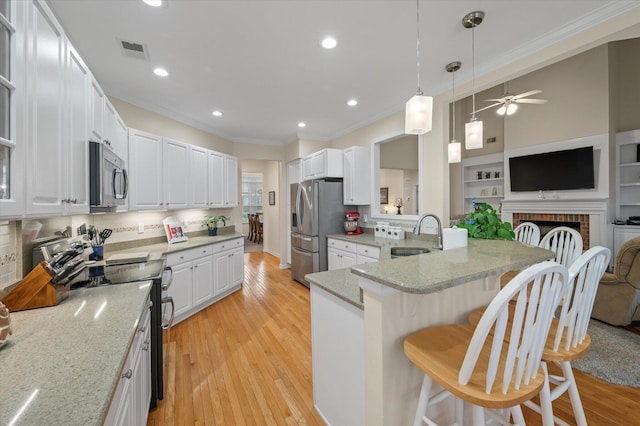 kitchen featuring stainless steel appliances, a sink, crown molding, a kitchen bar, and open floor plan