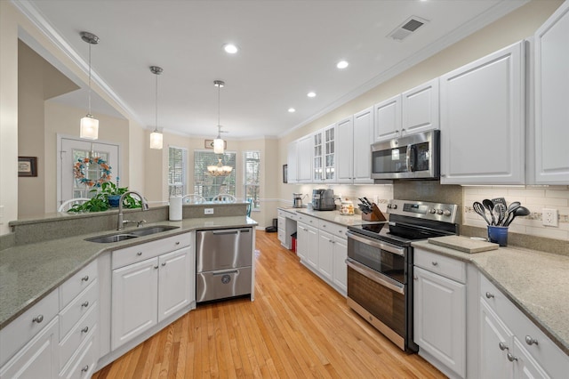 kitchen with stainless steel appliances, a sink, ornamental molding, light wood finished floors, and white cabinetry
