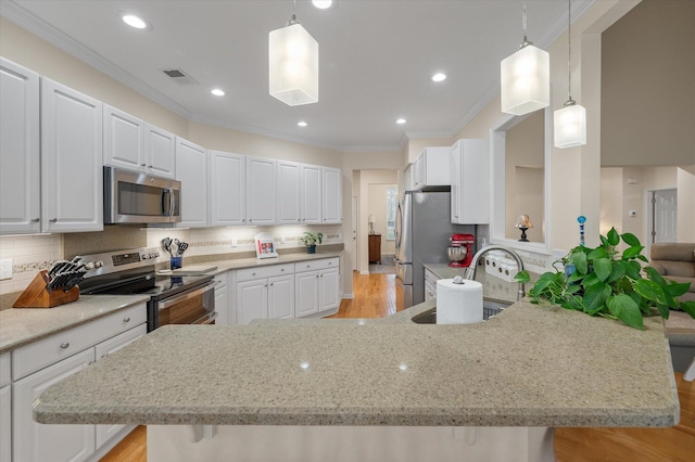 kitchen with appliances with stainless steel finishes, crown molding, a sink, light stone counters, and white cabinets