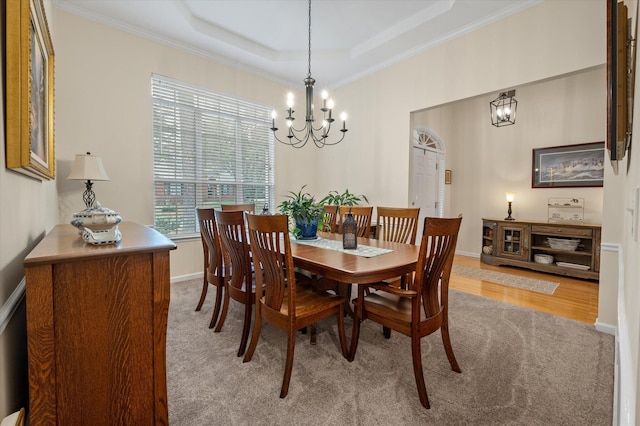 carpeted dining room featuring a chandelier, ornamental molding, a tray ceiling, and baseboards