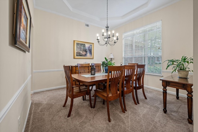 dining room featuring carpet, a chandelier, a raised ceiling, ornamental molding, and baseboards