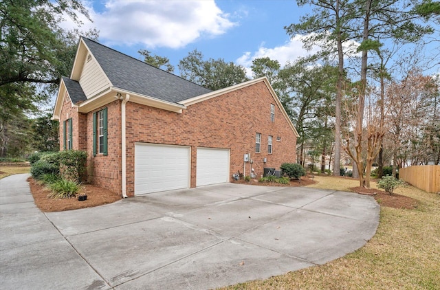 view of side of property with concrete driveway, roof with shingles, brick siding, an attached garage, and fence