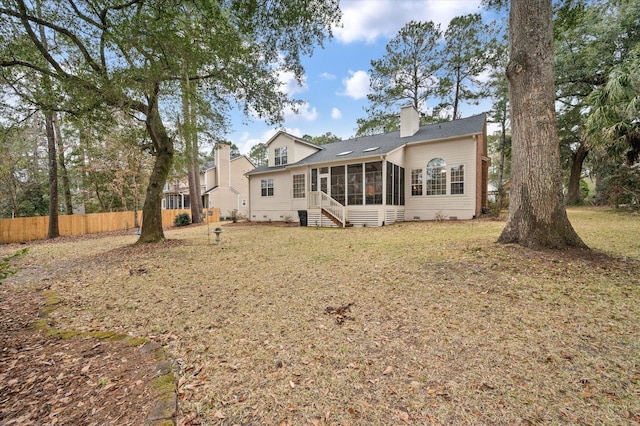 rear view of house with a sunroom and a chimney