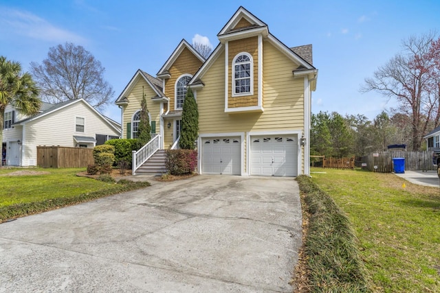 traditional-style house featuring a front lawn, concrete driveway, fence, and a garage