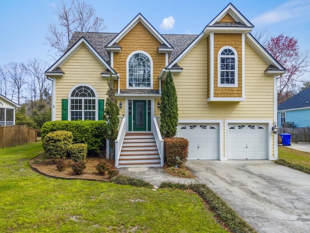 traditional-style home with fence, roof with shingles, concrete driveway, a front yard, and a garage