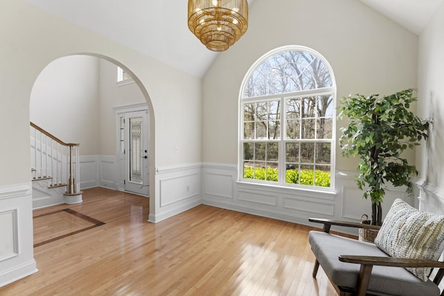 foyer featuring arched walkways, a healthy amount of sunlight, a chandelier, and light wood finished floors