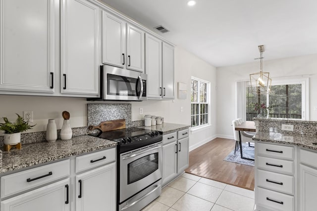 kitchen featuring light stone counters, light tile patterned floors, visible vents, stainless steel appliances, and white cabinets