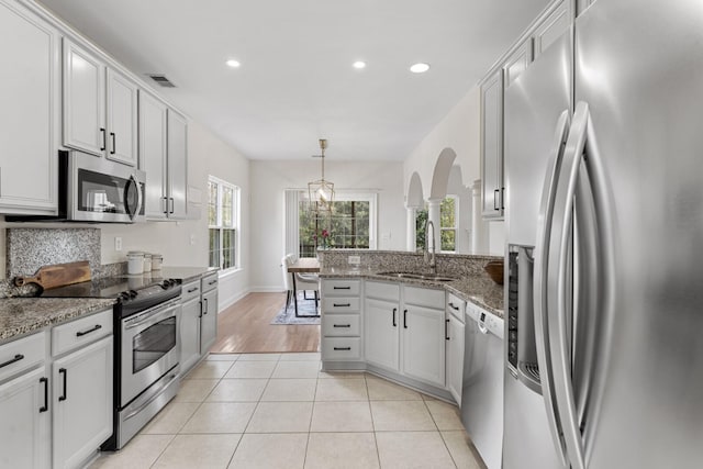 kitchen featuring visible vents, a sink, a peninsula, appliances with stainless steel finishes, and light tile patterned flooring