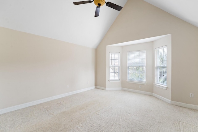 empty room featuring high vaulted ceiling, baseboards, a wealth of natural light, and light carpet