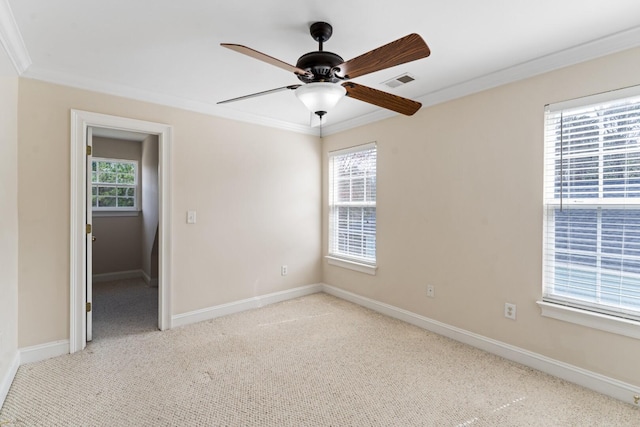 carpeted spare room with visible vents, a wealth of natural light, and ornamental molding