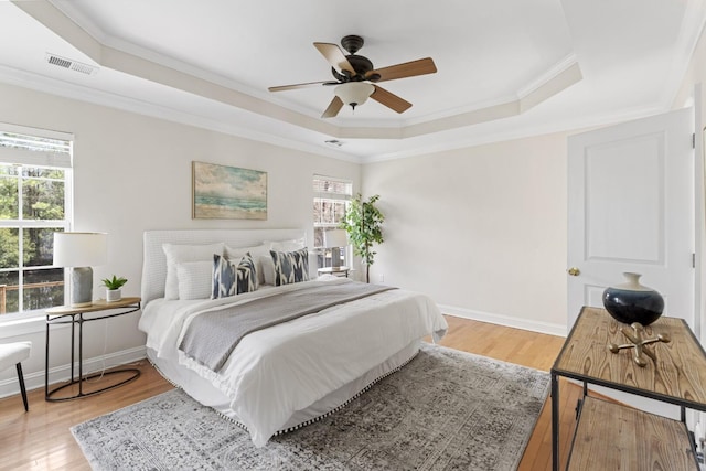 bedroom with a tray ceiling, multiple windows, and visible vents