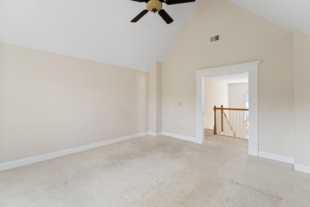 spare room with visible vents, baseboards, high vaulted ceiling, and light colored carpet