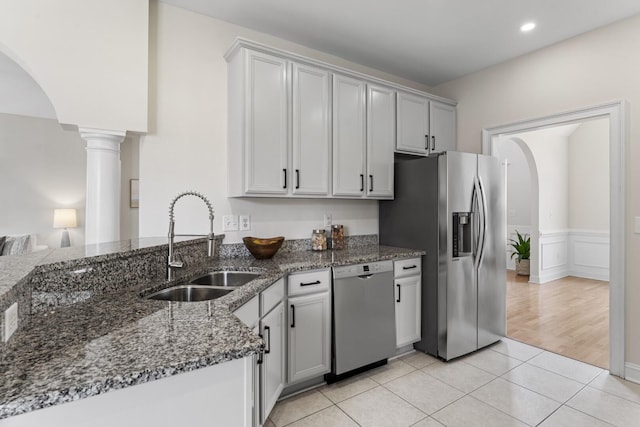 kitchen featuring a sink, stainless steel appliances, arched walkways, and decorative columns