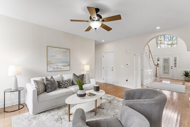 living area with light wood finished floors, stairway, recessed lighting, and arched walkways