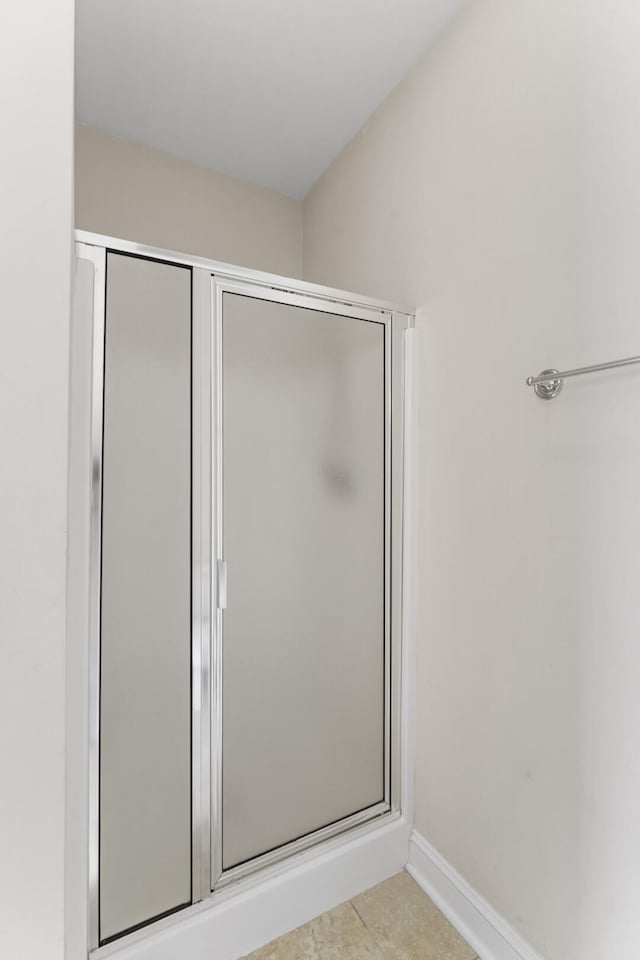 full bathroom featuring baseboards and a shower stall