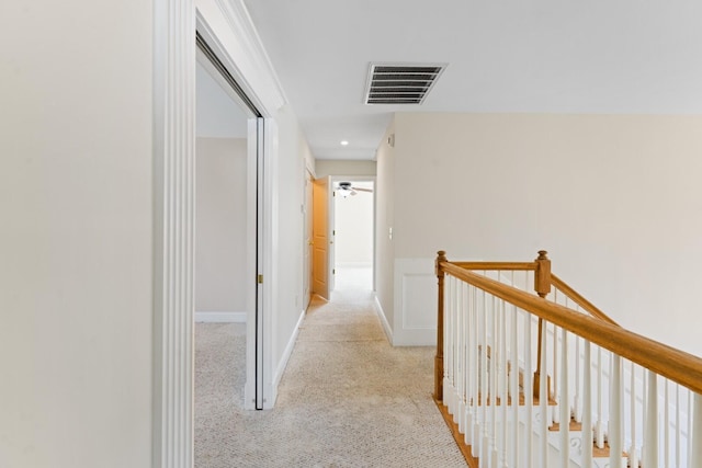 hallway with light colored carpet, an upstairs landing, and visible vents