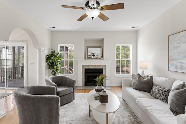 living area featuring decorative columns, light wood-style floors, and visible vents