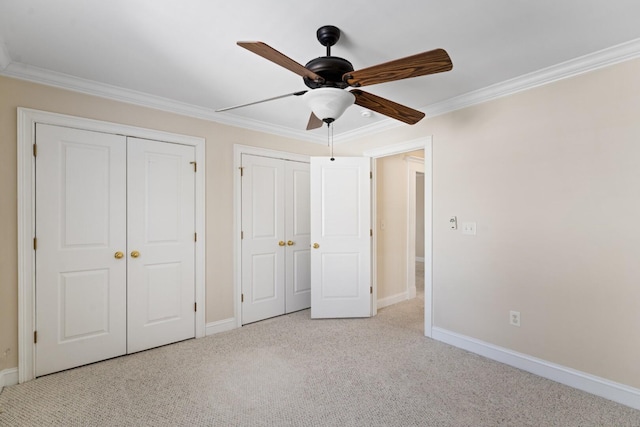 unfurnished bedroom with ornamental molding, two closets, baseboards, and carpet floors