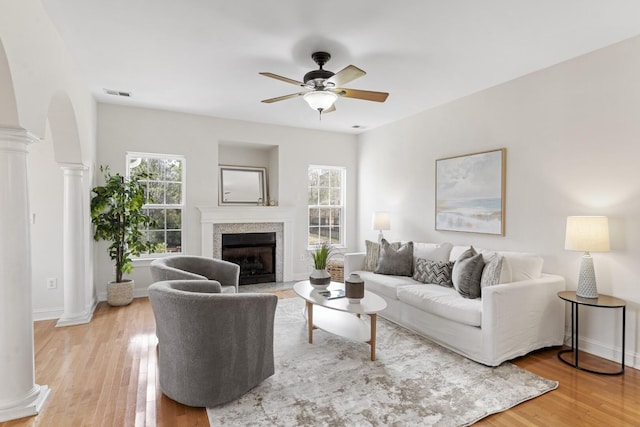 living area featuring plenty of natural light, light wood-type flooring, and ornate columns