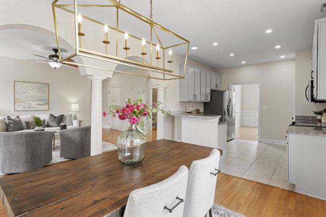 dining room featuring light wood-style flooring, recessed lighting, arched walkways, decorative columns, and ceiling fan