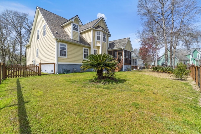 view of front of home with a front lawn, a fenced backyard, a sunroom, and a shingled roof