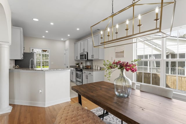 dining space with recessed lighting, light wood-style floors, and ornate columns