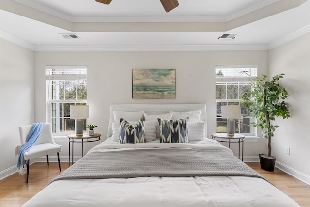 bedroom featuring visible vents, baseboards, a tray ceiling, and wood finished floors