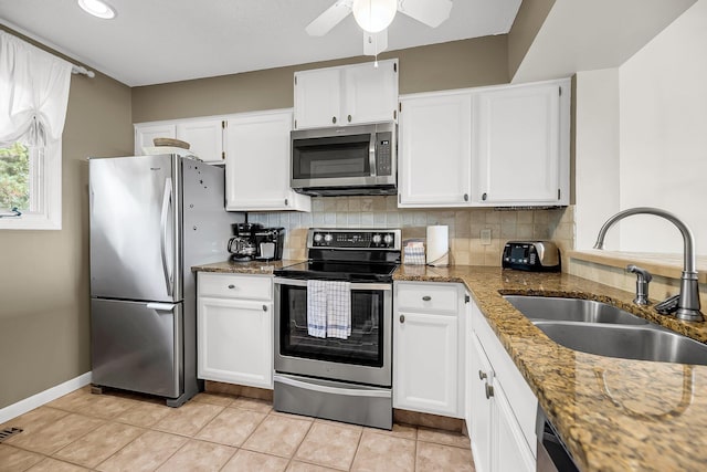 kitchen with decorative backsplash, white cabinets, dark stone counters, sink, and stainless steel appliances