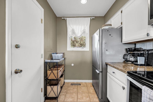 kitchen featuring tasteful backsplash, appliances with stainless steel finishes, dark stone counters, white cabinets, and light tile patterned floors