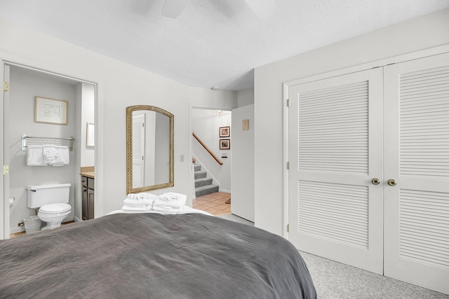 bedroom with light carpet, ceiling fan, a textured ceiling, and ensuite bath