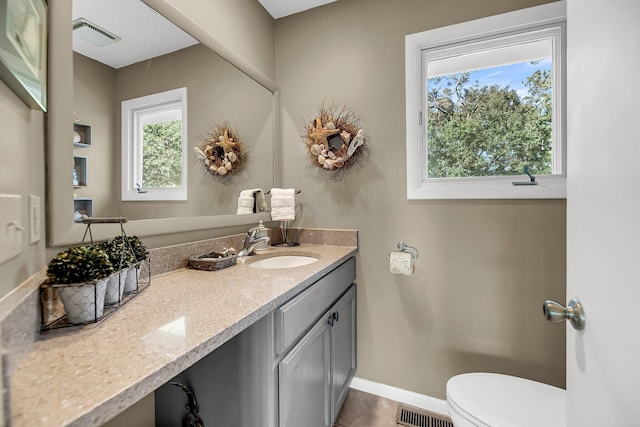 bathroom with a wealth of natural light, vanity, and toilet