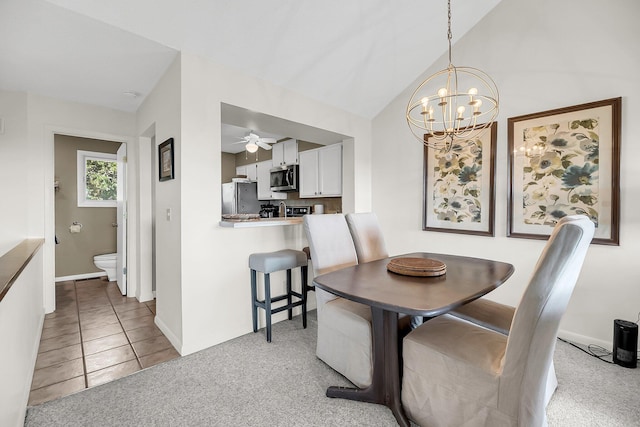 carpeted dining area featuring vaulted ceiling and ceiling fan with notable chandelier