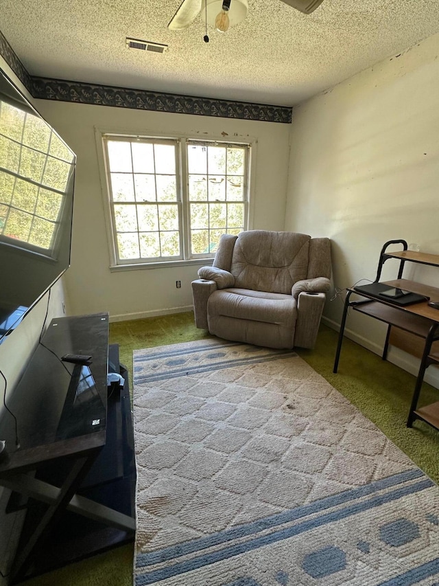 living area featuring visible vents, baseboards, ceiling fan, carpet, and a textured ceiling