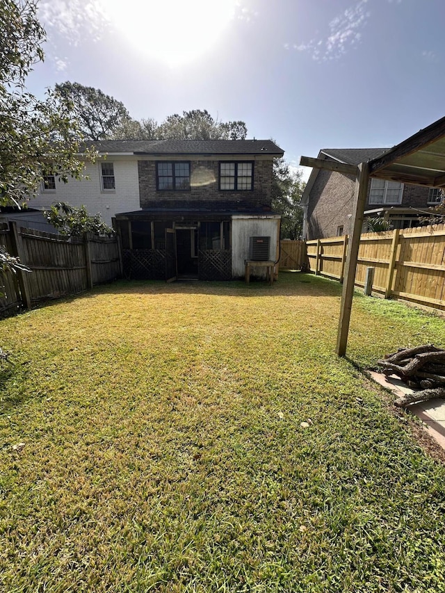 rear view of property with a lawn, brick siding, and a fenced backyard