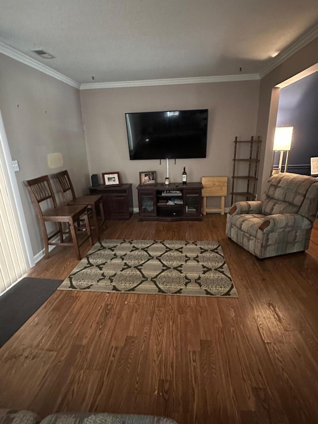 living area featuring visible vents, crown molding, baseboards, and wood finished floors