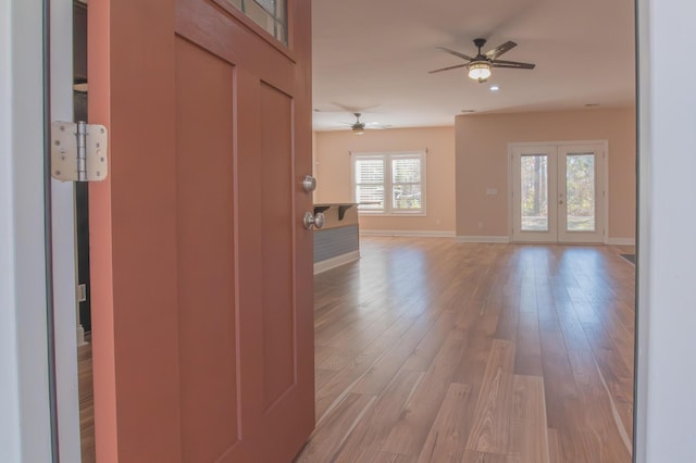 unfurnished living room with ceiling fan, light hardwood / wood-style flooring, and french doors