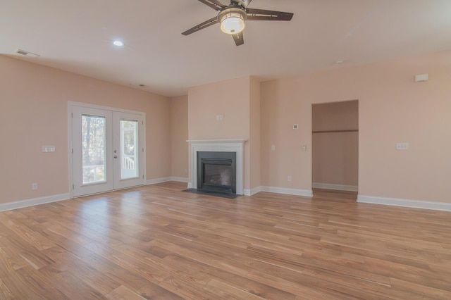 unfurnished living room with french doors, light wood-type flooring, and ceiling fan