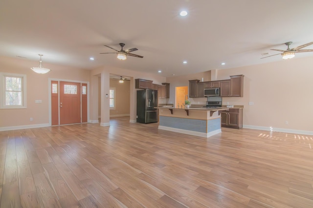 kitchen featuring pendant lighting, a kitchen island with sink, a breakfast bar area, light hardwood / wood-style floors, and stainless steel appliances