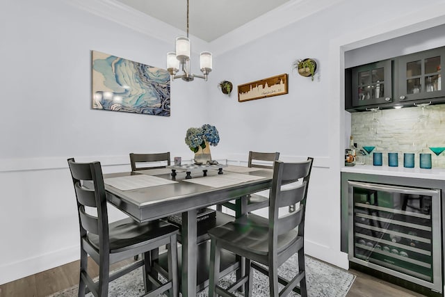 dining area with crown molding, an inviting chandelier, bar area, dark hardwood / wood-style floors, and beverage cooler