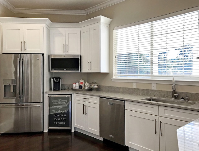 kitchen with white cabinetry, dark hardwood / wood-style flooring, stainless steel appliances, sink, and ornamental molding