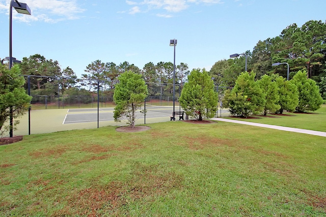 view of property's community featuring tennis court and a yard