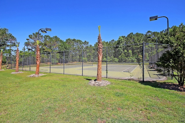 view of tennis court with a yard