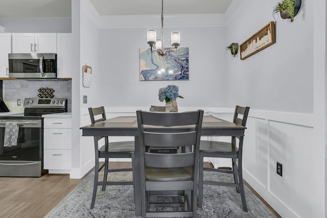 dining space featuring ornamental molding, a notable chandelier, and light wood-type flooring